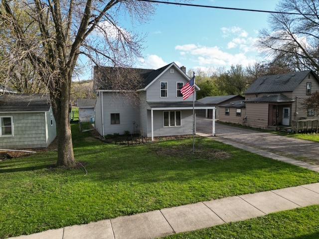 220 Front St E, Redwood Falls, MN 56283 - traditional-style home featuring concrete driveway, a front yard, a chimney, and an attached carport