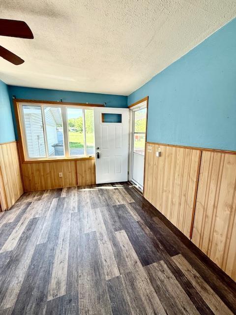 220 Front St E, Redwood Falls, MN 56283 - spare room featuring a textured ceiling, a wainscoted wall, wood finished floors, wood walls, and a ceiling fan
