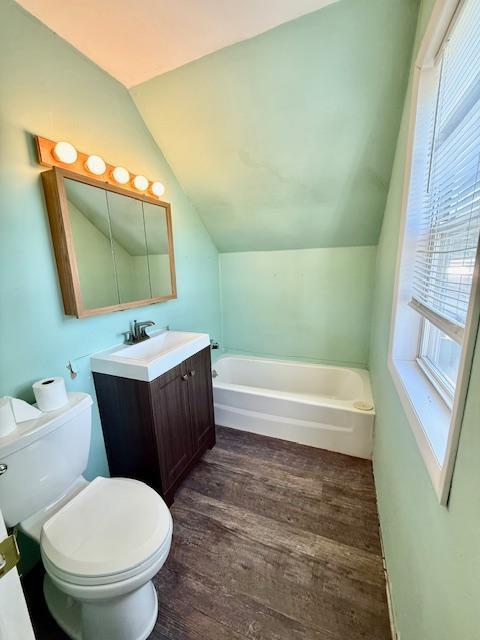 220 Front St E, Redwood Falls, MN 56283 - bathroom with toilet, a bath, vaulted ceiling, vanity, and wood finished floors