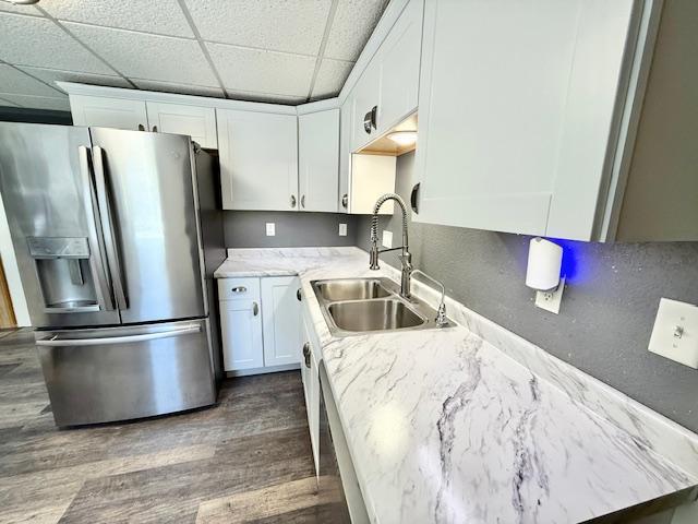 220 Front St E, Redwood Falls, MN 56283 - kitchen with stainless steel fridge with ice dispenser, a sink, a paneled ceiling, white cabinets, and wood finished floors