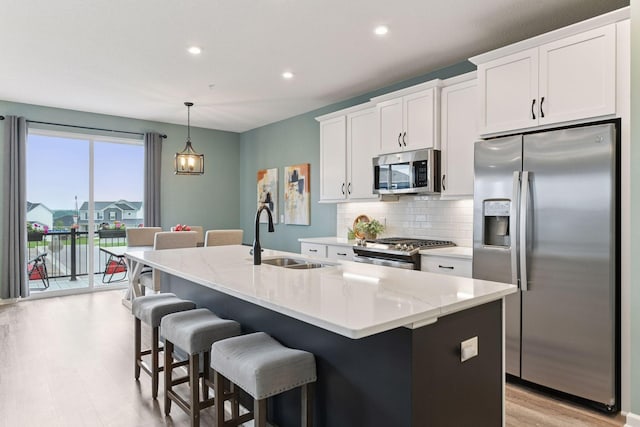 6678 Wildflower Way, Minnetrista, MN 55331 - kitchen with stainless steel appliances, an island with sink, backsplash, white cabinets, and a breakfast bar