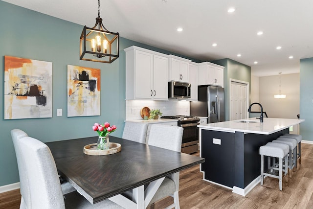 6678 Wildflower Way, Minnetrista, MN 55331 - kitchen featuring stainless steel appliances, a chandelier, wood finished floors, a kitchen island with sink, and recessed lighting