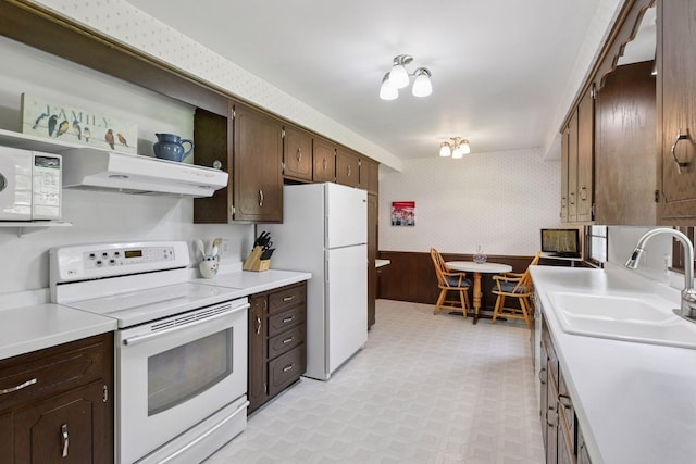 5456 Twin Lake Blvd E, Brooklyn Center, MN 55429 - kitchen with white appliances, light flooring, wallpapered walls, under cabinet range hood, and dark brown cabinetry