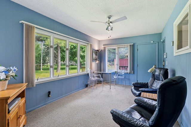 5456 Twin Lake Blvd E, Brooklyn Center, MN 55429 - sitting room featuring ceiling fan, plenty of natural light, carpet flooring, and wood walls