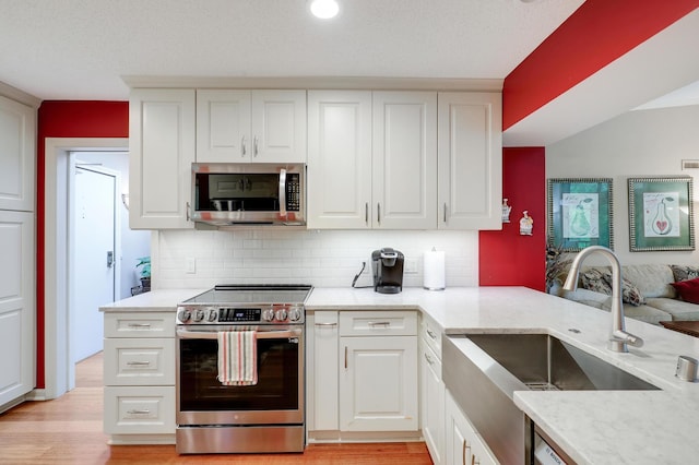 5601 Dewey Hill Rd Unit 310, Edina, MN 55439 - kitchen with appliances with stainless steel finishes, a sink, tasteful backsplash, light wood finished floors, and white cabinets