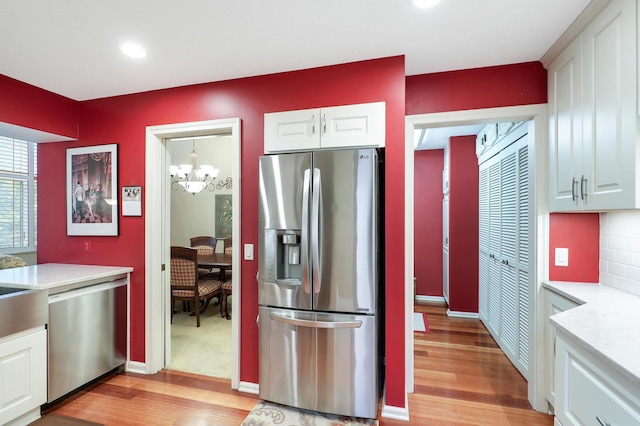 5601 Dewey Hill Rd Unit 310, Edina, MN 55439 - kitchen with stainless steel appliances, light wood finished floors, white cabinets, light countertops, and a chandelier
