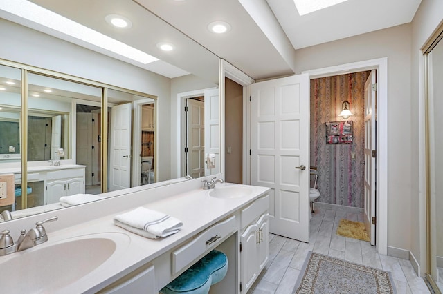 5601 Dewey Hill Rd Unit 310, Edina, MN 55439 - full bathroom featuring toilet, double vanity, baseboards, recessed lighting, and a skylight