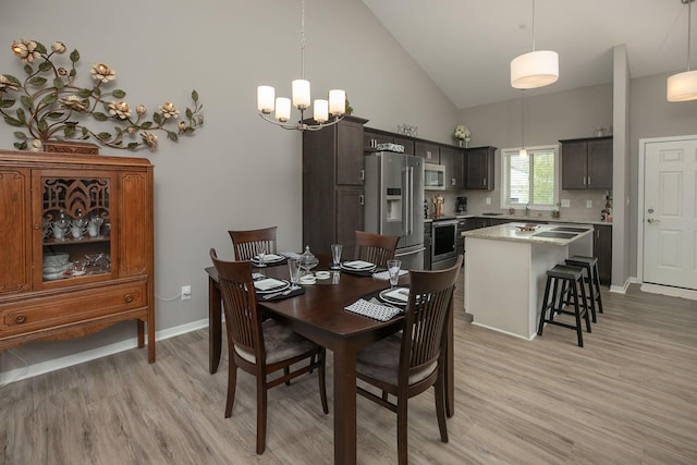 1217 Sundance Ct NE, Byron, MN 55920 - dining space featuring light wood-style floors, a chandelier, high vaulted ceiling, and baseboards