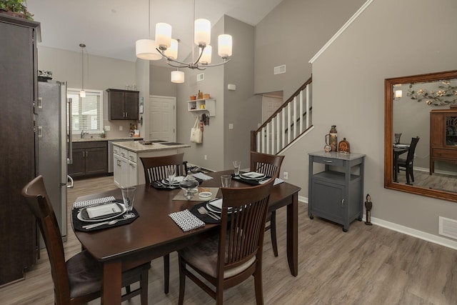 1217 Sundance Ct NE, Byron, MN 55920 - dining area with high vaulted ceiling, light wood-style floors, a chandelier, stairs, and baseboards