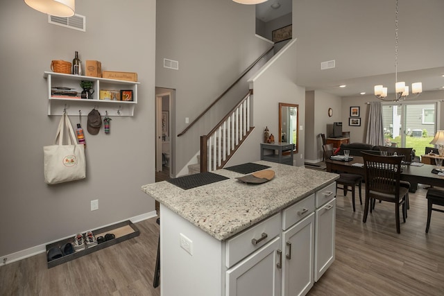 1217 Sundance Ct NE, Byron, MN 55920 - kitchen featuring a high ceiling, a chandelier, wood finished floors, a kitchen island, and pendant lighting