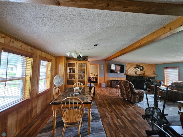 4732 San Juan Dr, Fargo, ND 58103 - dining area featuring wood walls, a fireplace, wood finished floors, beam ceiling, and a textured ceiling