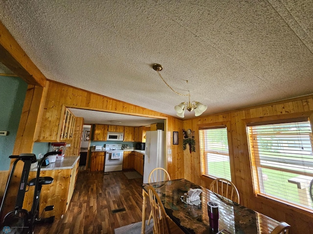 4732 San Juan Dr, Fargo, ND 58103 - dining space featuring wooden walls, vaulted ceiling, dark wood-type flooring, a textured ceiling, and a chandelier