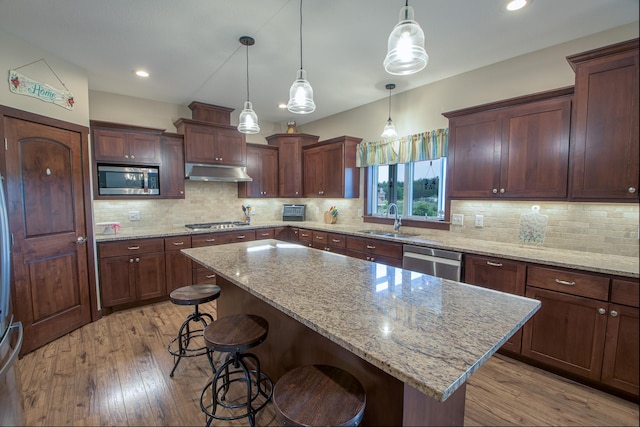 2142 Monarch Ct, Sartell, MN 56377 - kitchen with appliances with stainless steel finishes, a sink, a kitchen bar, under cabinet range hood, and recessed lighting