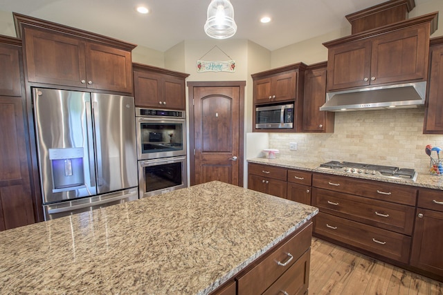 2142 Monarch Ct, Sartell, MN 56377 - kitchen featuring appliances with stainless steel finishes, under cabinet range hood, tasteful backsplash, light stone countertops, and light wood-style floors