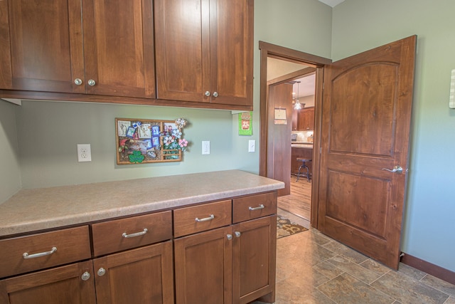 2142 Monarch Ct, Sartell, MN 56377 - kitchen with light countertops, baseboards, brown cabinetry, and dark stone finish floors