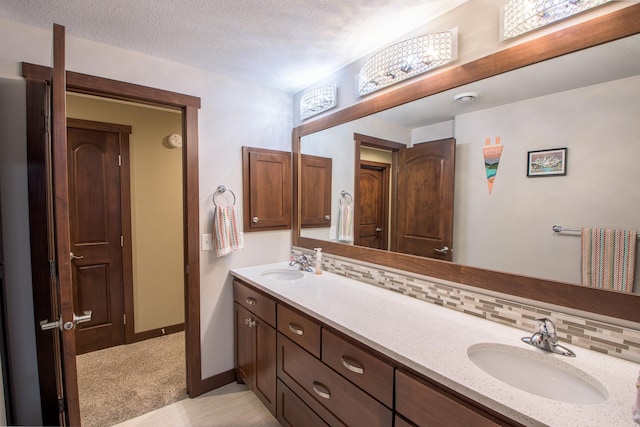 2142 Monarch Ct, Sartell, MN 56377 - full bath featuring double vanity, baseboards, tasteful backsplash, and a textured ceiling