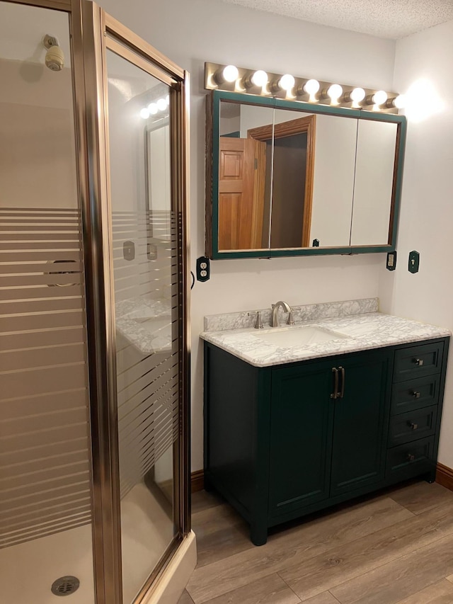 903 2nd St, Princeton, MN 55371 - bathroom with vanity, wood finished floors, a shower stall, and a textured ceiling