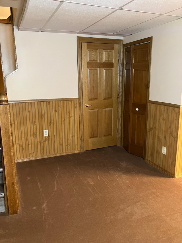 903 2nd St, Princeton, MN 55371 - carpeted spare room featuring wainscoting, wooden walls, a paneled ceiling, and baseboards