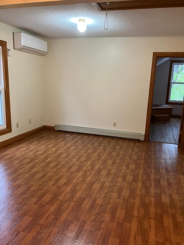 903 2nd St, Princeton, MN 55371 - unfurnished room with a wall unit AC, a baseboard heating unit, dark wood finished floors, baseboards, and a textured ceiling