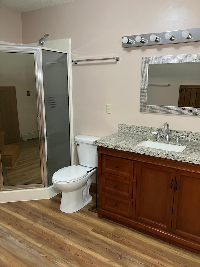 903 2nd St, Princeton, MN 55371 - bathroom with vanity, toilet, a stall shower, and wood finished floors