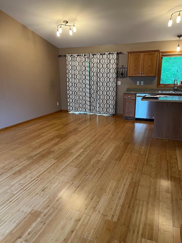 205 Darling Pl, Alexandria, MN 56308 - kitchen with stainless steel dishwasher, a sink, light wood-style floors, brown cabinets, and open floor plan