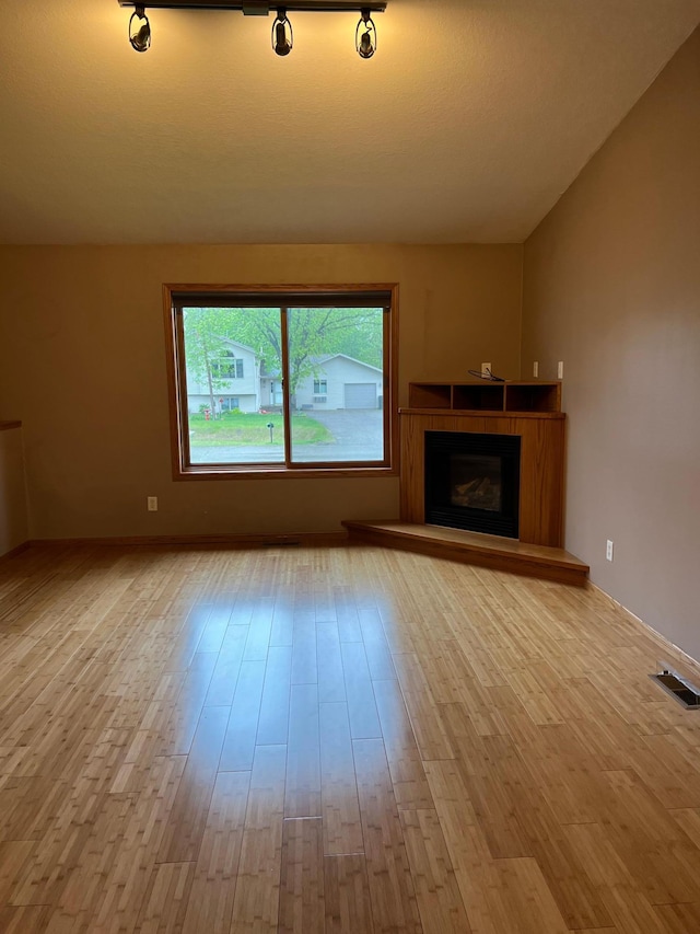 205 Darling Pl, Alexandria, MN 56308 - unfurnished living room with wood finished floors, vaulted ceiling, and a fireplace with raised hearth