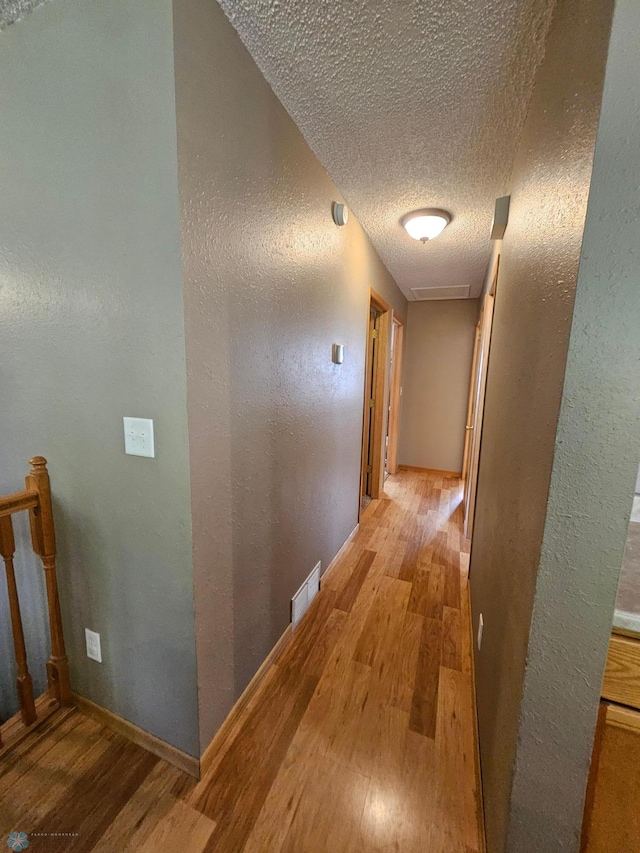 2904 17th Ave S, Moorhead, MN 56560 - hall featuring light wood finished floors, a textured ceiling, a textured wall, baseboards, and an upstairs landing