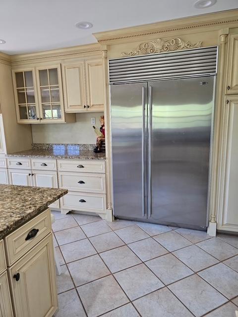 28320 State Highway 65, Pengilly, MN 55775 - kitchen featuring stainless steel built in refrigerator, cream cabinets, light tile patterned floors, glass insert cabinets, and dark stone counters