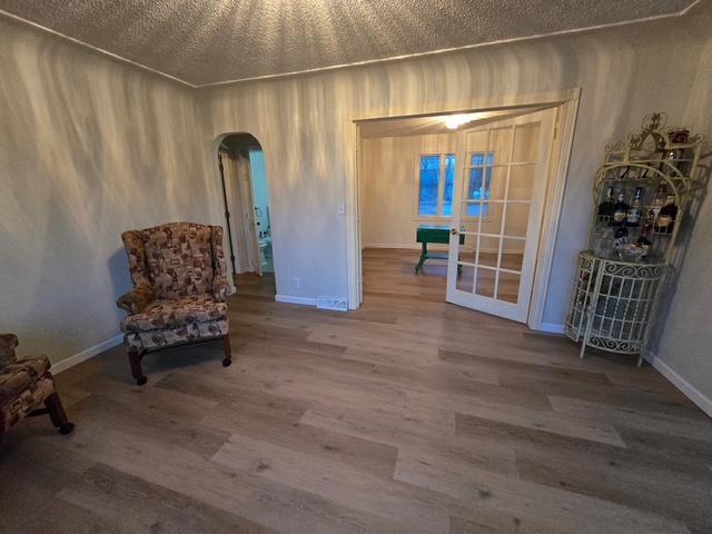 28320 State Highway 65, Pengilly, MN 55775 - sitting room with arched walkways, wood finished floors, baseboards, french doors, and a textured ceiling