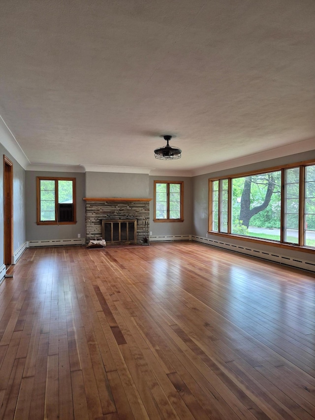 227 Summit Ave, Grantsburg, WI 54840 - unfurnished living room featuring hardwood / wood-style floors, a baseboard radiator, baseboards, crown molding, and a fireplace
