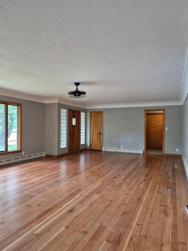 227 Summit Ave, Grantsburg, WI 54840 - unfurnished living room featuring baseboard heating, light wood finished floors, baseboards, and ornamental molding