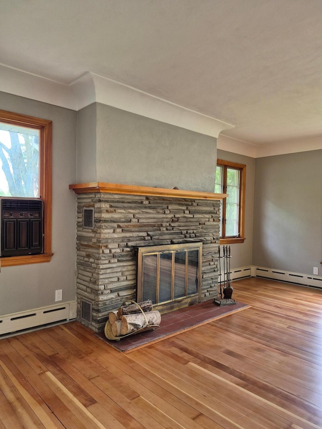 227 Summit Ave, Grantsburg, WI 54840 - unfurnished living room with a stone fireplace, a baseboard radiator, wood-type flooring, and cooling unit