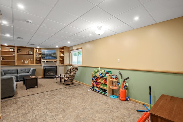 2572 91st Ln NE, Blaine, MN 55449 - rec room featuring built in shelves, a glass covered fireplace, baseboards, a drop ceiling, and recessed lighting