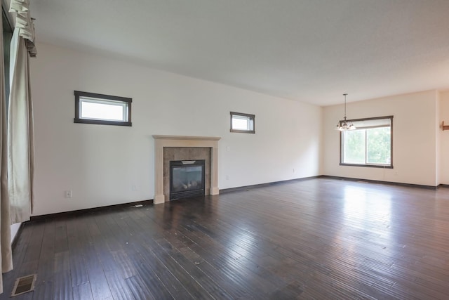 12396 67th St NE, Otsego, MN 55330 - unfurnished living room with a chandelier, a tiled fireplace, dark wood-type flooring, and baseboards