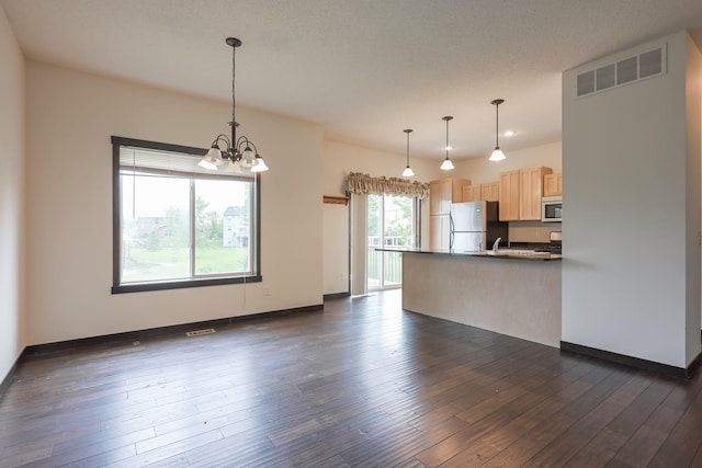 12396 67th St NE, Otsego, MN 55330 - kitchen with freestanding refrigerator, light brown cabinetry, white microwave, dark countertops, and a peninsula