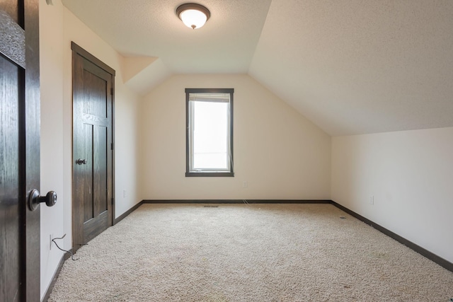 12396 67th St NE, Otsego, MN 55330 - bonus room featuring light colored carpet, lofted ceiling, baseboards, and a textured ceiling