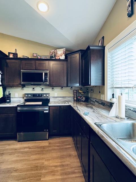1320 Whiting Rd NW Unit 41, Bemidji, MN 56601 - kitchen with appliances with stainless steel finishes, vaulted ceiling, light countertops, a sink, and light wood-style flooring