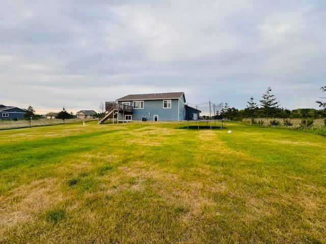 1320 Whiting Rd NW Unit 41, Bemidji, MN 56601 - back of house featuring stairway, a trampoline, a deck, and a lawn