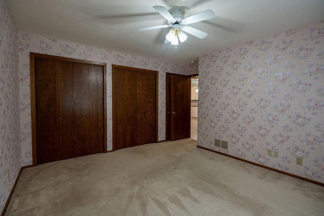 2851 120th Ave SW, Willmar, MN 56201 - unfurnished bedroom with carpet flooring, two closets, wallpapered walls, a ceiling fan, and baseboards
