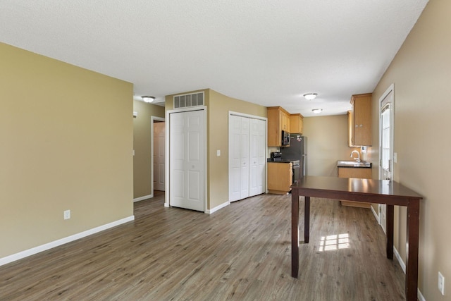 6670 84th Ct N, Brooklyn Park, MN 55445 - kitchen featuring wood finished floors, baseboards, a sink, and stainless steel microwave