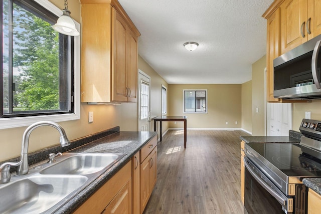 6670 84th Ct N, Brooklyn Park, MN 55445 - kitchen with appliances with stainless steel finishes, a sink, plenty of natural light, dark countertops, and a textured ceiling