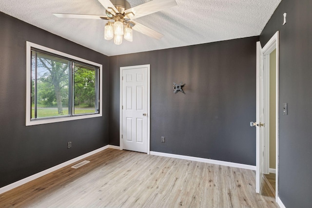 6670 84th Ct N, Brooklyn Park, MN 55445 - spare room featuring light wood-style flooring, a ceiling fan, baseboards, and a textured ceiling