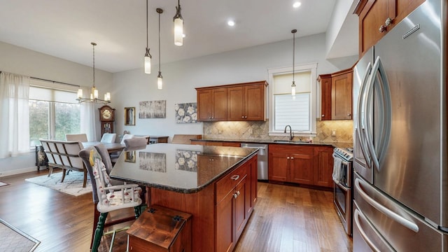 1829 Traders Point Ln SW, Rochester, MN 55902 - kitchen with stainless steel appliances, a sink, a kitchen island, decorative backsplash, and dark wood finished floors