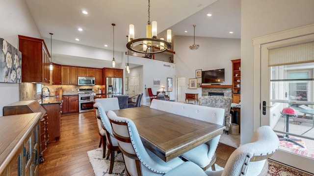 1829 Traders Point Ln SW, Rochester, MN 55902 - dining room featuring a chandelier, wood finished floors, high vaulted ceiling, a stone fireplace, and recessed lighting