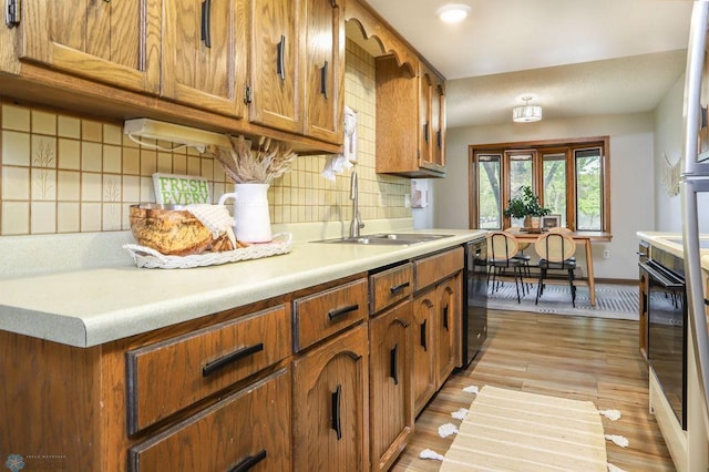 220 8th St S Unit B2, Fargo, ND 58103 - kitchen with a sink, dishwasher, brown cabinets, light countertops, and decorative backsplash
