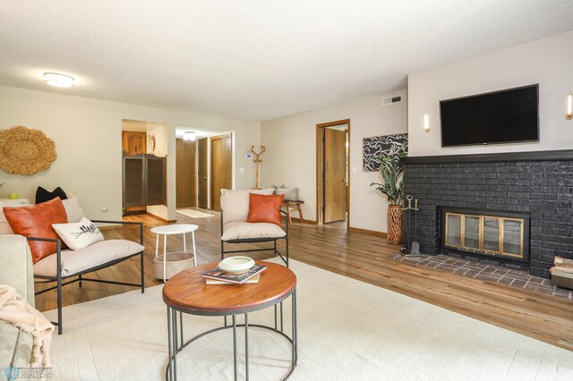 220 8th St S Unit B2, Fargo, ND 58103 - living area featuring wood finished floors, a brick fireplace, a textured ceiling, and baseboards