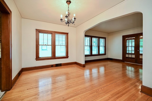 919 Howard St, Winona, MN 55987 - empty room with arched walkways, a chandelier, light wood-type flooring, and baseboards