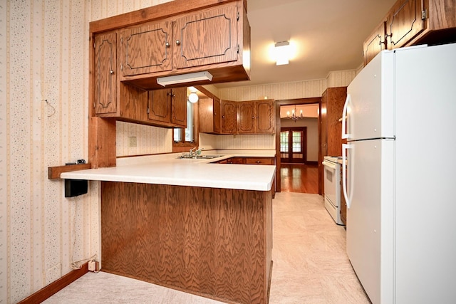 919 Howard St, Winona, MN 55987 - kitchen with white appliances, wallpapered walls, a peninsula, light countertops, and a chandelier
