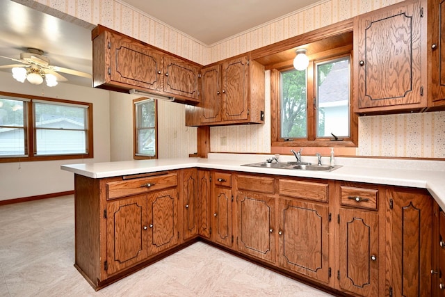 919 Howard St, Winona, MN 55987 - kitchen with wallpapered walls, a sink, a peninsula, brown cabinets, and plenty of natural light