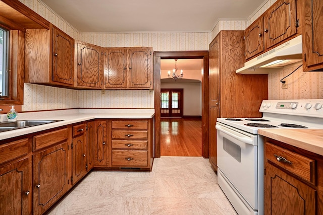 919 Howard St, Winona, MN 55987 - kitchen with electric range, under cabinet range hood, wallpapered walls, a chandelier, and brown cabinetry